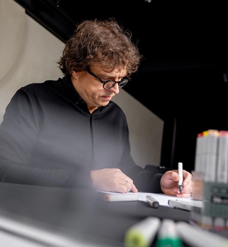 Een man zit aan tafel en tekent