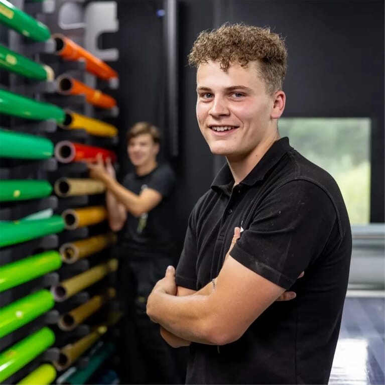 Een man met zijn armen over elkaar in een werkgomgeving