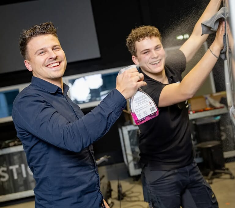 Twee mannen maken lachend iets schoon