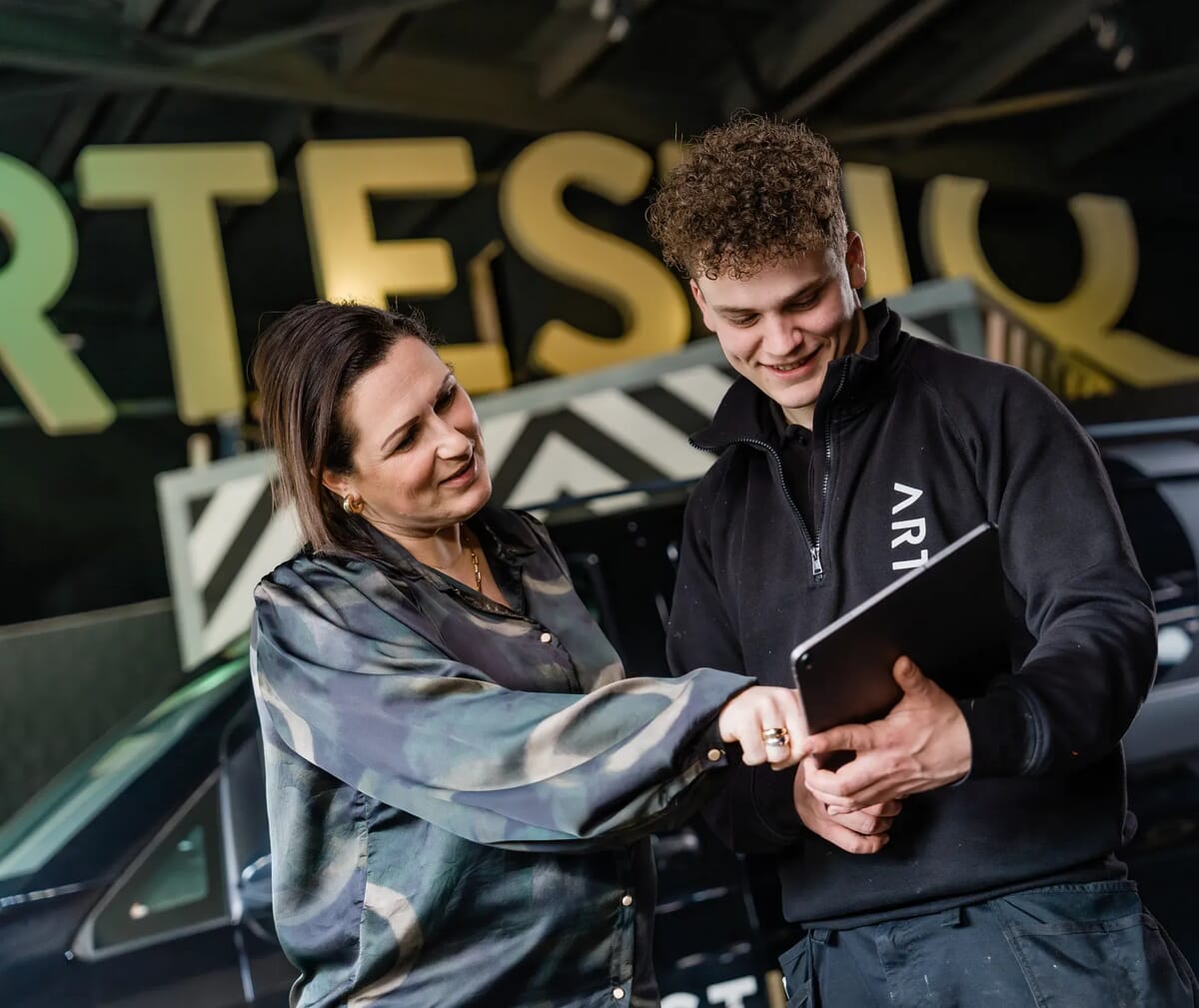 Vrouw kijkt mee op tablet en lacht