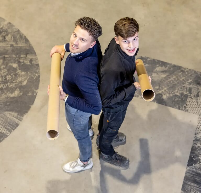 Twee mannen met de rug tegen elkaar aan en kijken omhoog