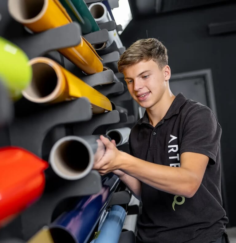 Een jongen staat bij een muur met allemaal folierollen