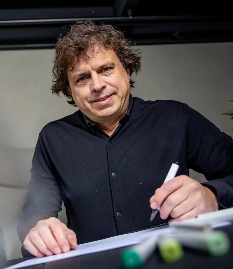 Man tekent op papier en kijk camera in