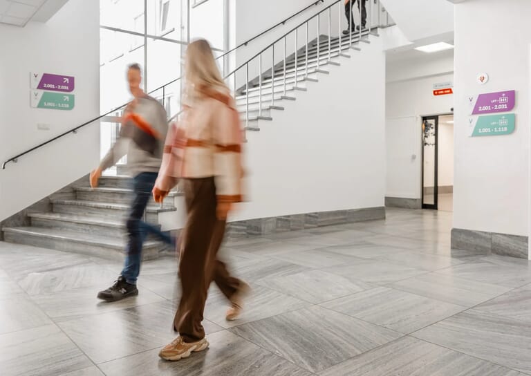 Er lopen personen in een ruimte langs