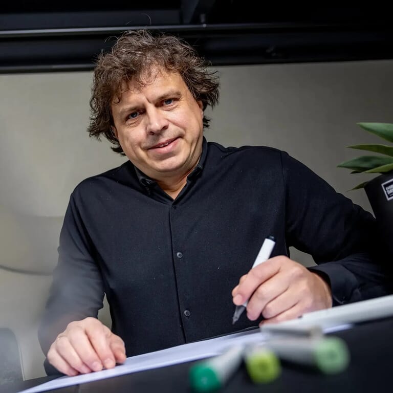 Man tekent op papier en kijk camera in