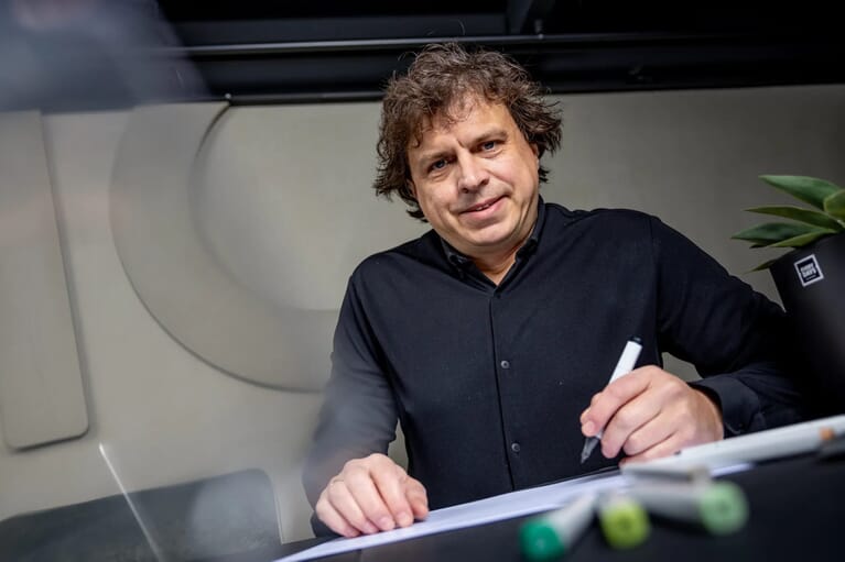 Man tekent op papier en kijk camera in