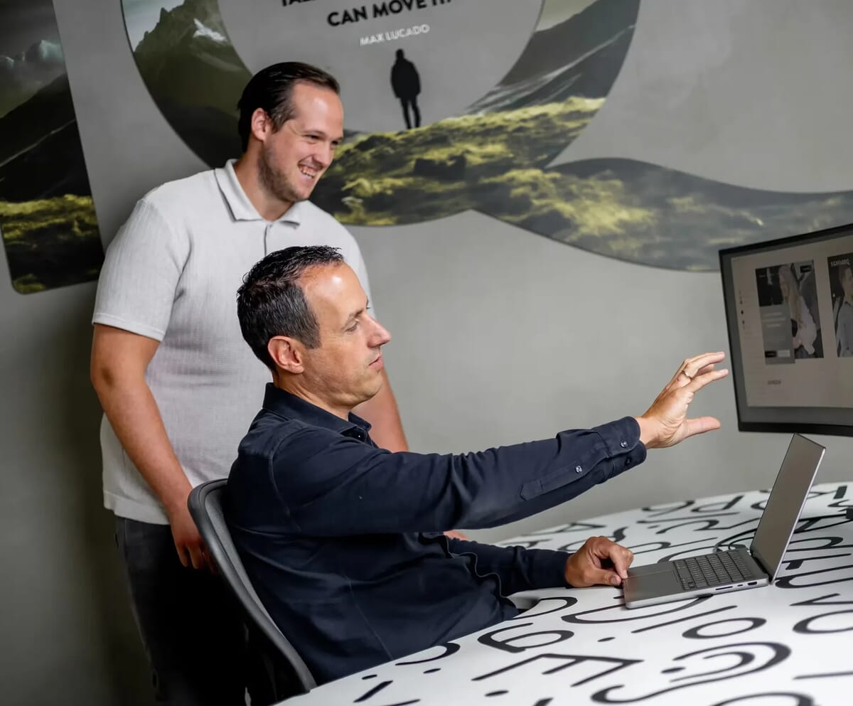 Twee mannen achter een bureau kijken naar een beeldscherm