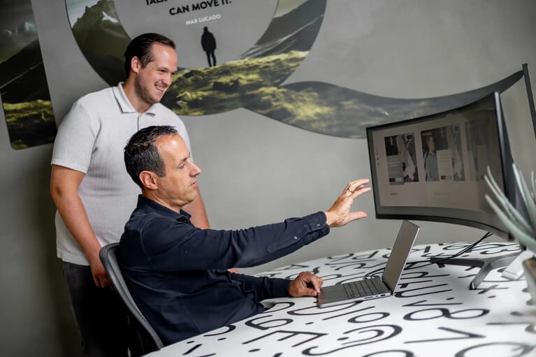 Twee mensen bij een bureau kijken naar een beeldscherm