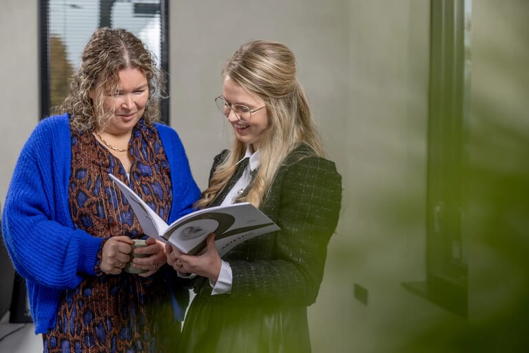 twee vrouwen naast elkaar kijken in een magazine