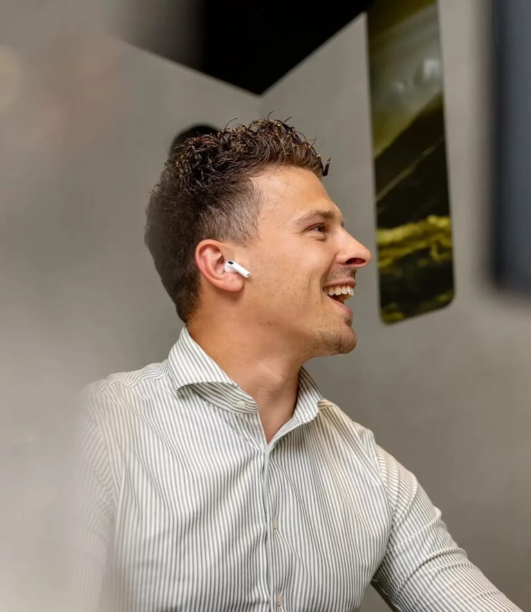 Een man lacht en heeft oordopjes in