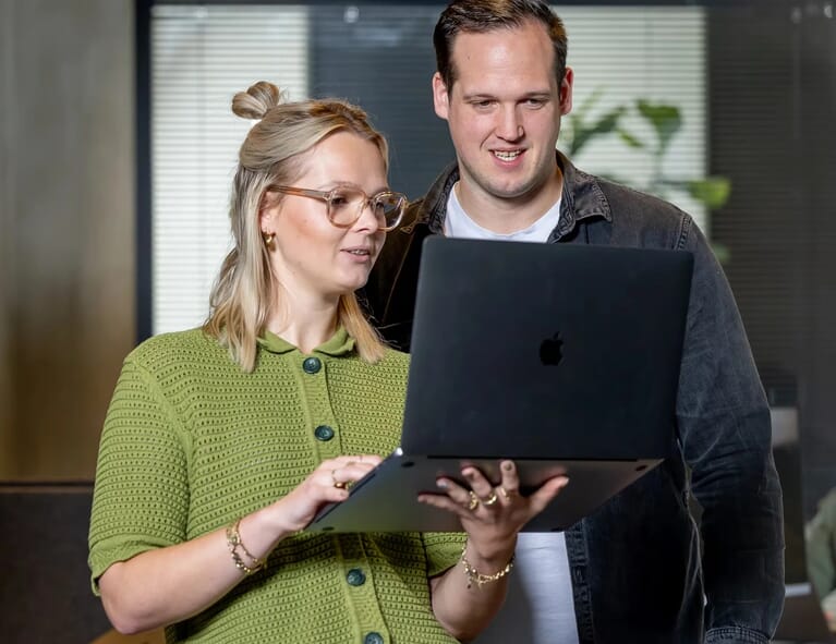 Twee mensen overleggen met elkaar met een laptop in de hand
