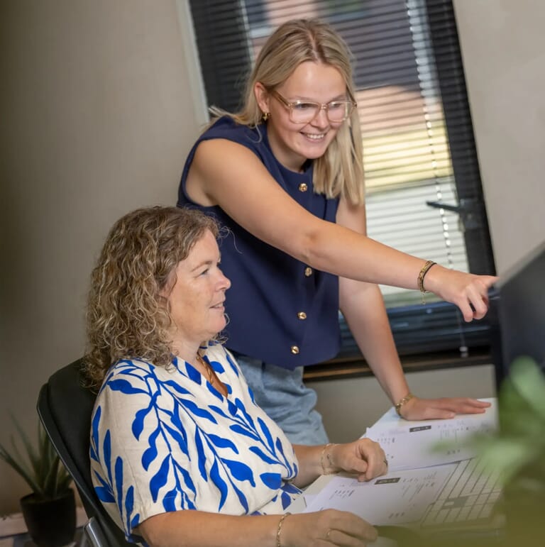 Twee collegas kijken naar een computer scherm