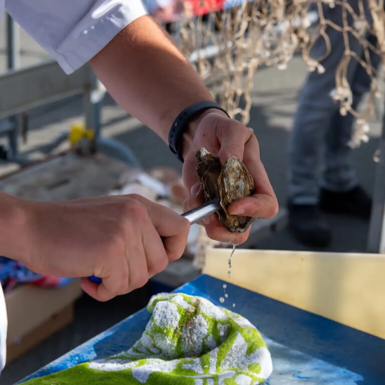 Iemand die een oester openmaakt