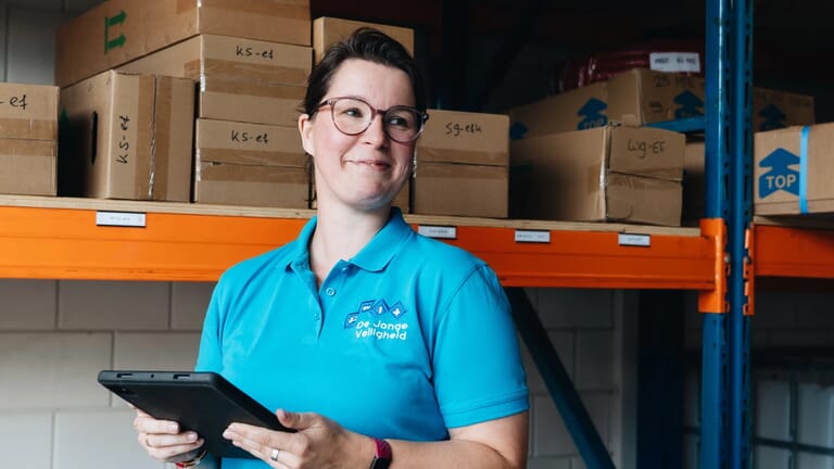 Een vrouw voor een stelling met een tablet in de hand
