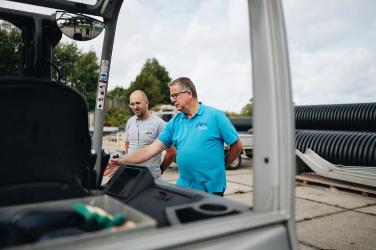 Foto van twee mannen voor een voertuig