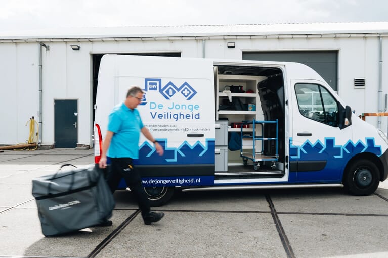 Man loopt met een koffer langs een openstaande bus