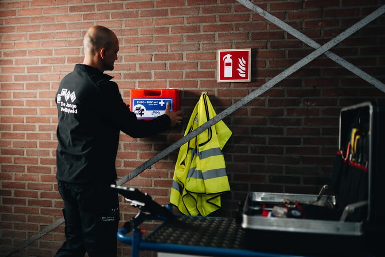 Een man houdt een verbandkoffer vast