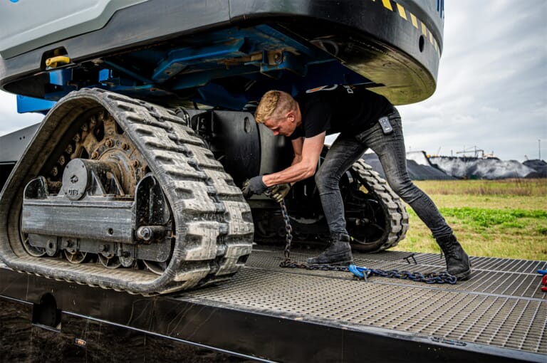 Man zet een hoogwerkers vast op de vrachtwagen met kettingen