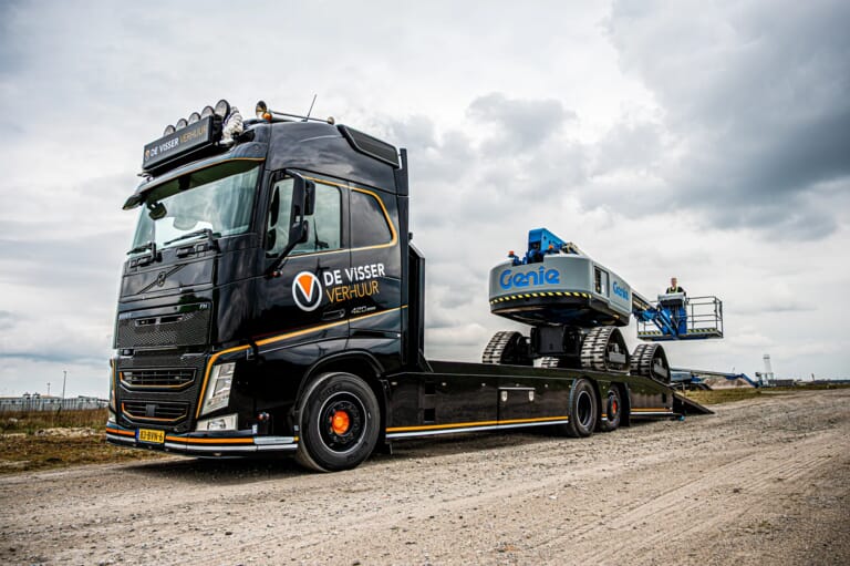 Een zwarte vrachtwagen met daarop een hoogwerker