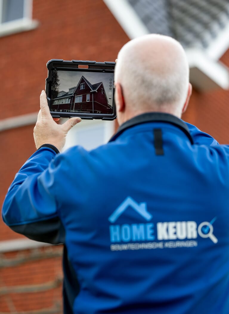 Man met een ipad die het huis fotografeert