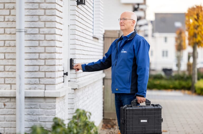 Een inspecteur die voor de deur staat en op de bel drukt