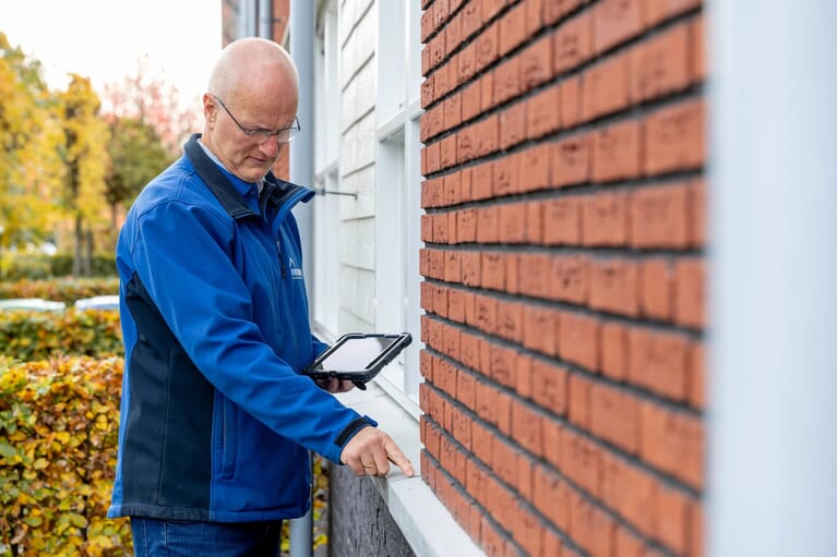 Man inspecteert de buitenkant van een huis