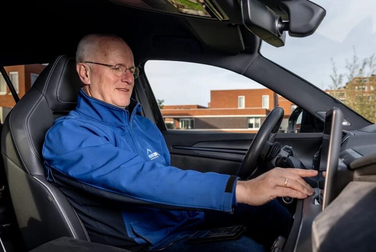 Man in een auto toetst iets in op de navigatie