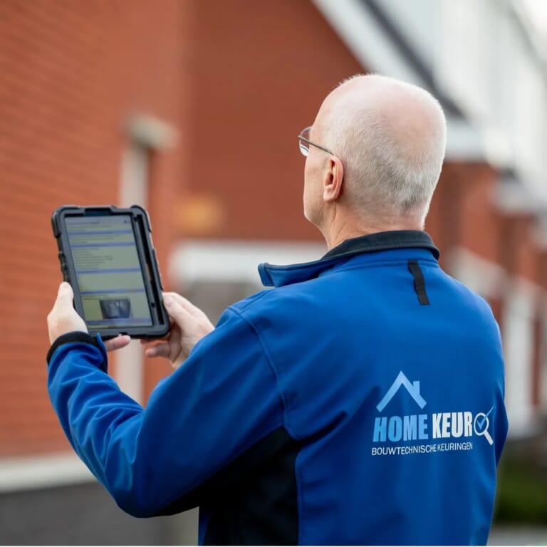 Een man heeft een tablet in de hand en kijk naar een huis