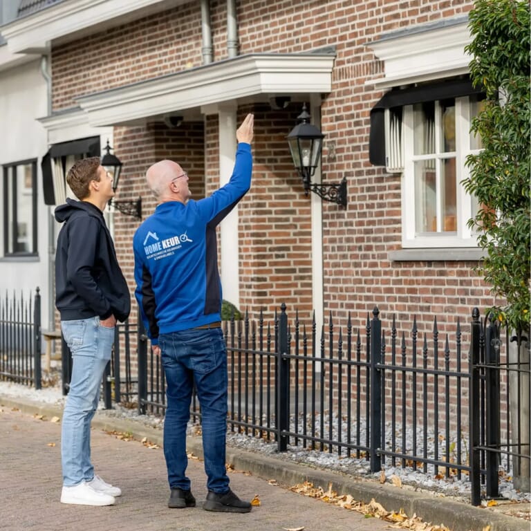 Mensen kijken omhoog naar een huis en een man wijst