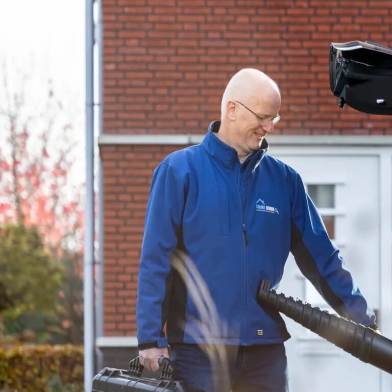 Man haalt iets uit zijn auto en heeft een zwarte koffer vast