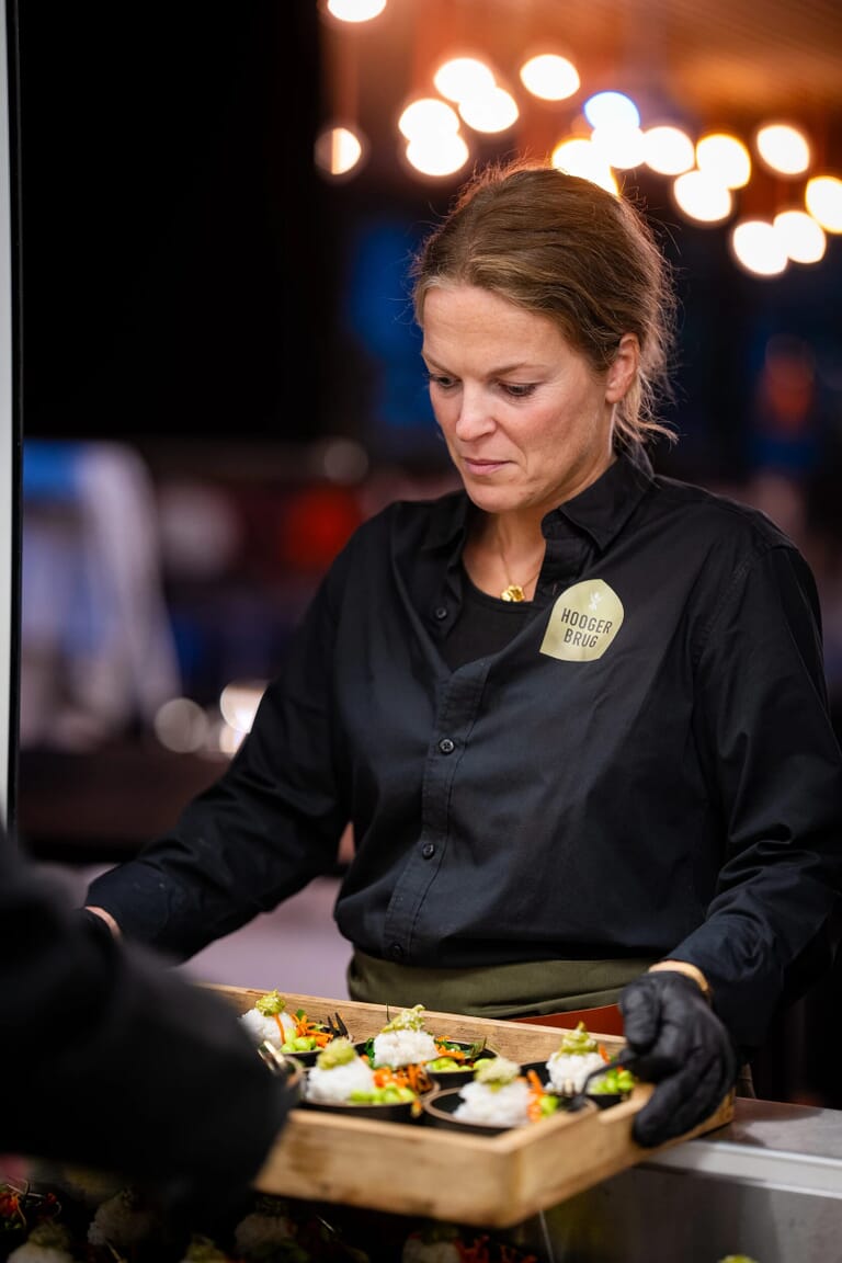 Een medewerker heeft een krat vast met kleine gerechtjes