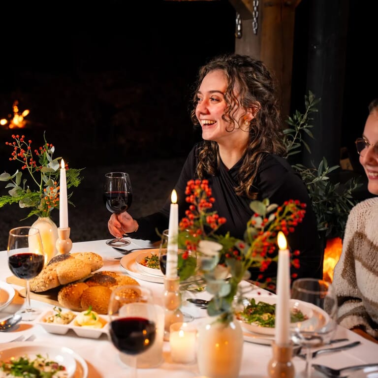 Vrouw zit aan een gedekte tafel en lacht