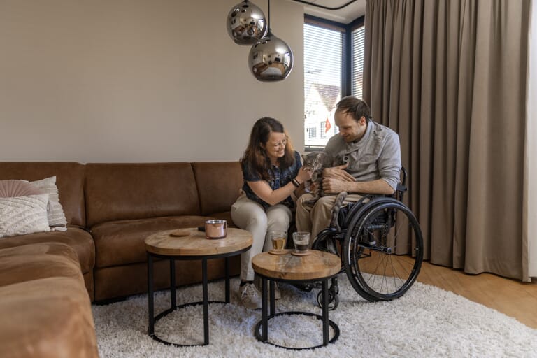 man-in-rolstoel-met-kat-en-vrouw-ontzorgt-in-zorgwoning