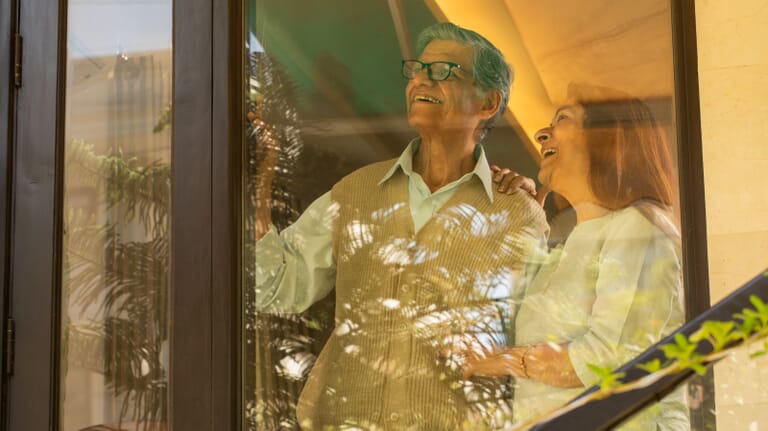 ouder-stel-kijkt-blij-uit-raam