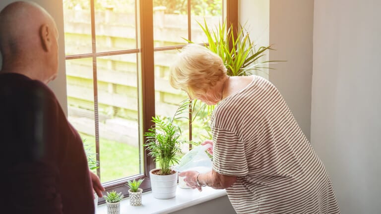 oudere-vrouw-geeft-plantjes-water-in-zorgeenheid