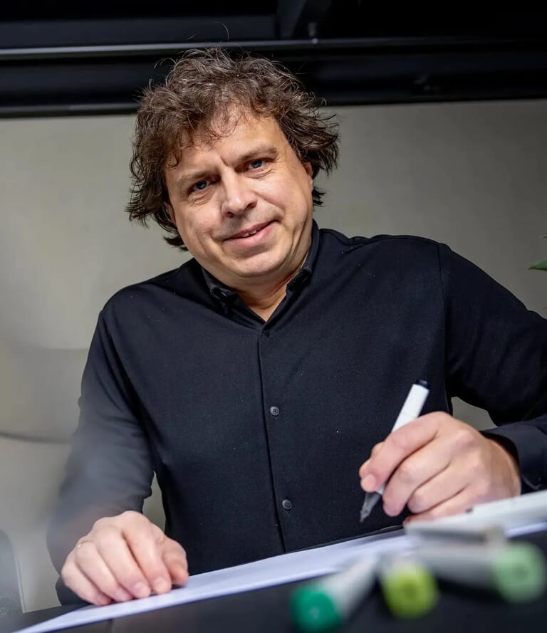 Man tekent op papier en kijk camera in