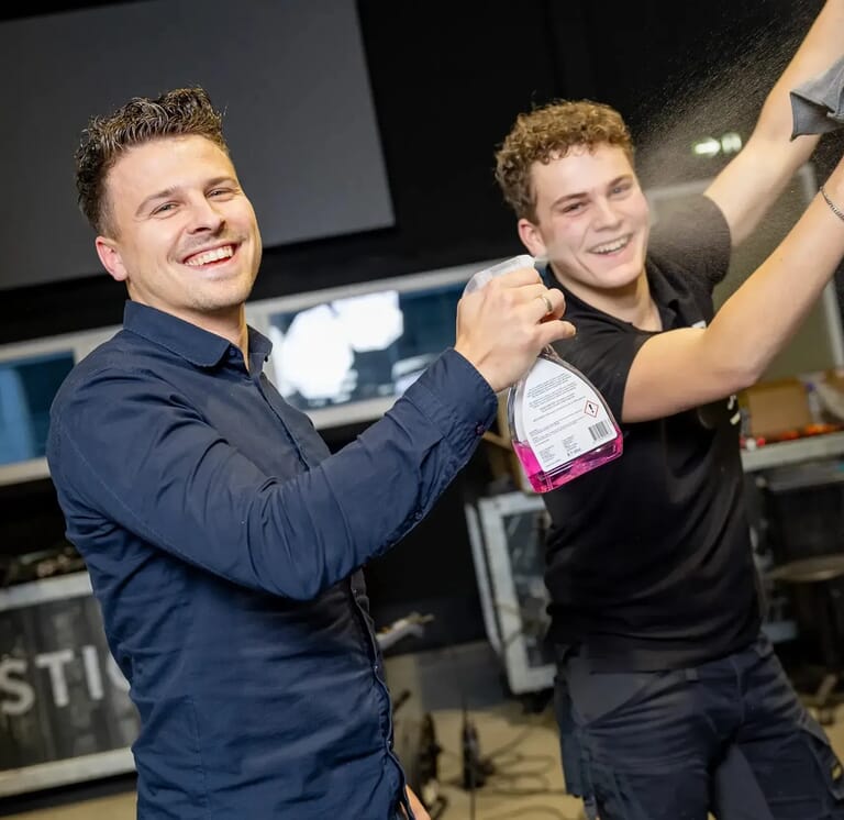 Twee mannen maken lachend iets schoon
