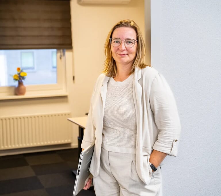 Een vrouw in de opening van een deurgat met een laptop onder haar arm