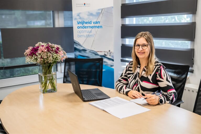 Een vrouw aan een tafel met een laptop en documenten voor zich