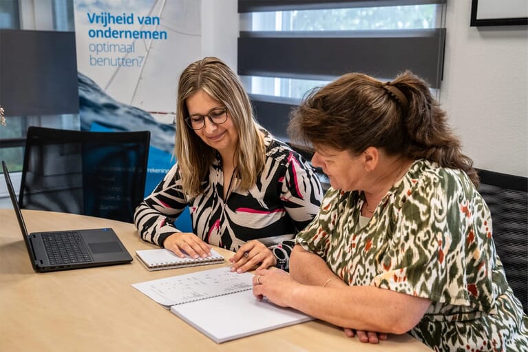 twee vrouwen aan een bureau die documenten doornemen