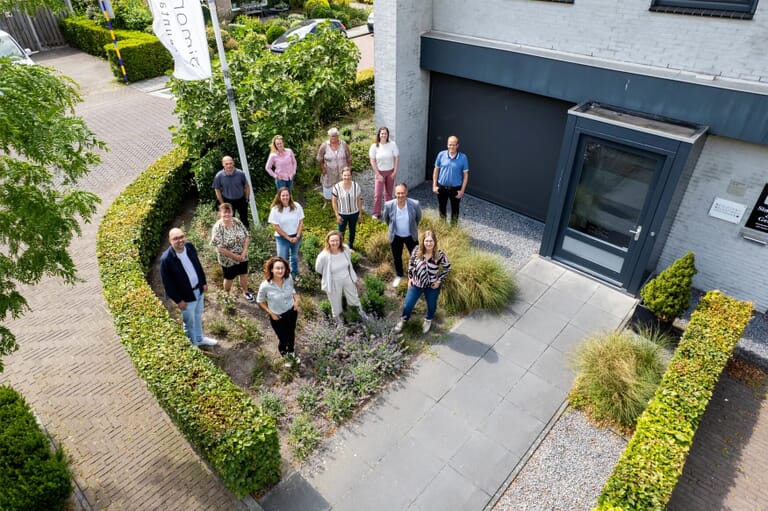 Groep mensen kijkt naar boven in een voortuin