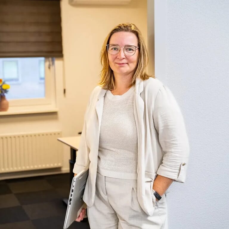 Een vrouw in de opening van een deurgat met een laptop onder haar arm
