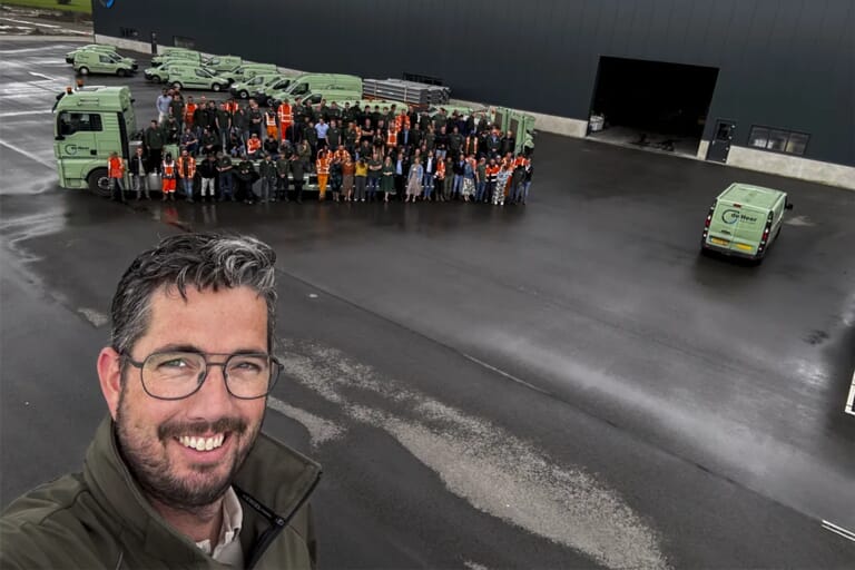 Een man met op de achtergrond een grote groep mensen op een industrieterrein 
