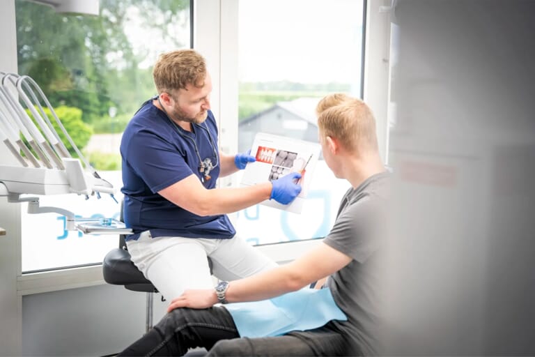 Een tandarts die de foto's van het gebit aan de patiënt laat zien