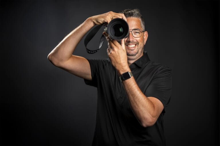 Een lachende man achter een camera