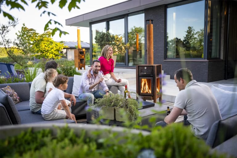 Mensen in een tuin op een loungebank die lachen en pizza eten