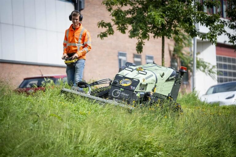 Een jongen in werkkleding met de afstandsbediening van een automatische maaier