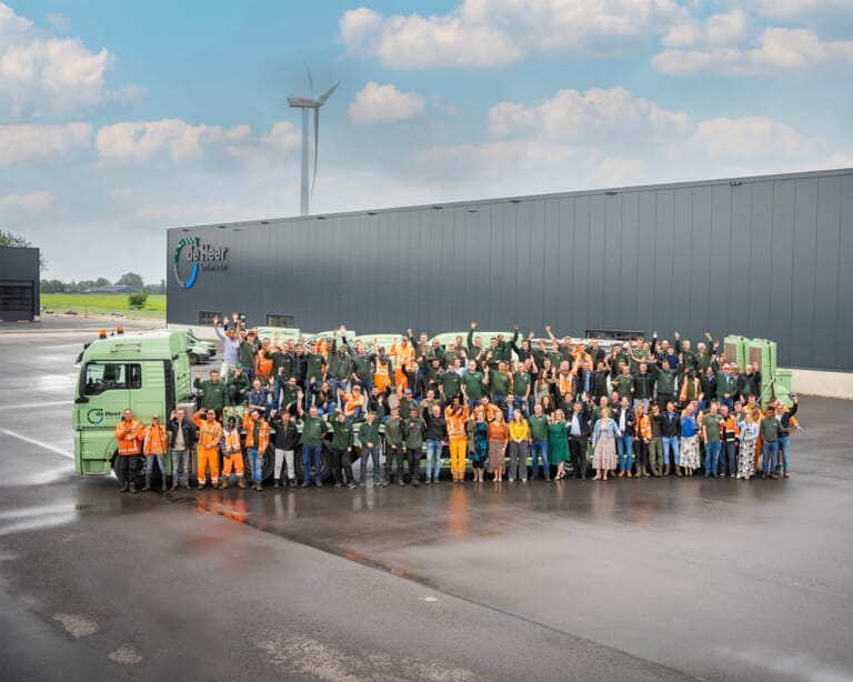 Een grote groep mensen voor en op een vrachtwagen op een industrieterrein