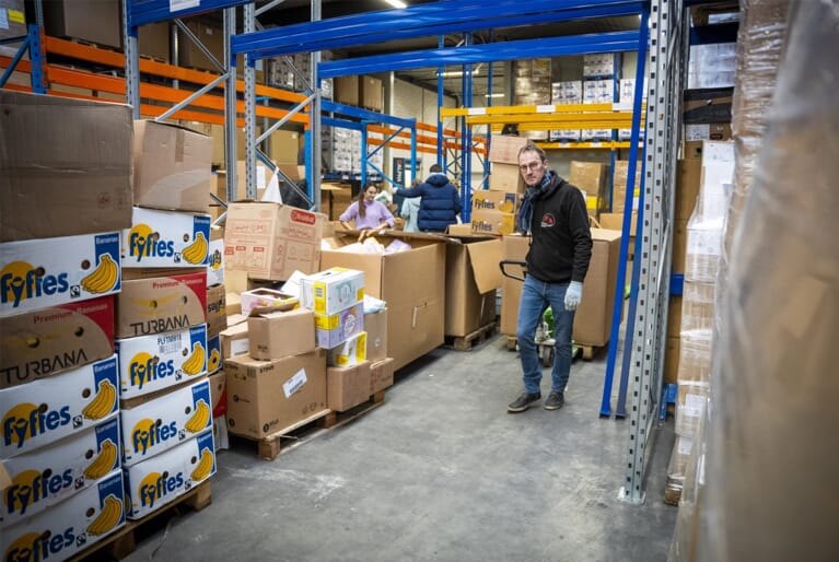 Een man in een ruimte met allemaal pallets met karton