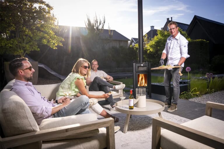 Mensen in een tuin op een loungebank die lachen en pizza eten